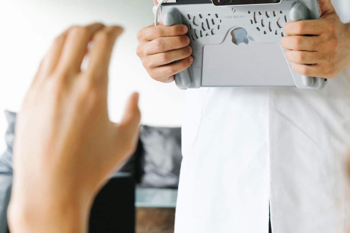 Professionnel de santé tenant une tablette médicale face à un patient